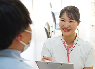 職員が入居者と対面で対応している風景。タブレットを持ち、笑顔で接客中。
